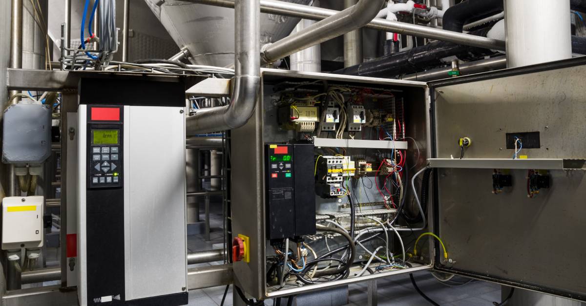 Two frequency converters installed in an industrial setting. One device is open to reveal several multicolored wires.